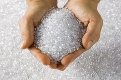 Hands holding transparent plastic resin pellets used in packaging and manufacturing.